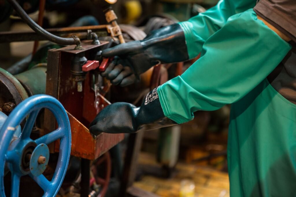 Trabalhador com luvas de proteção operando válvula industrial