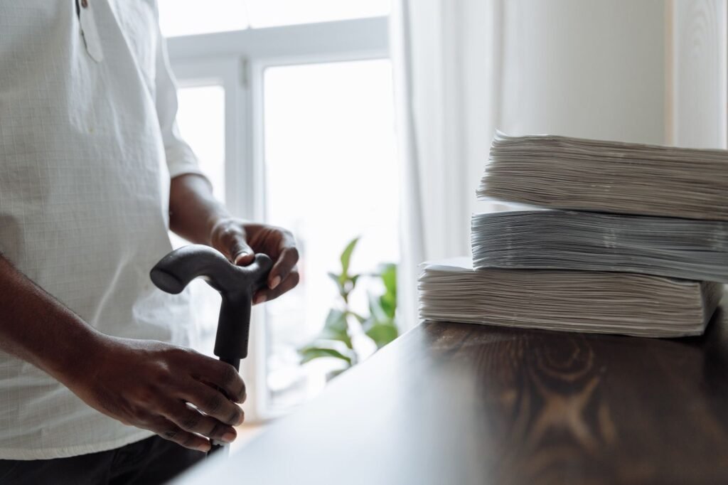 Mão de homem segurando uma bengala junto à mesa