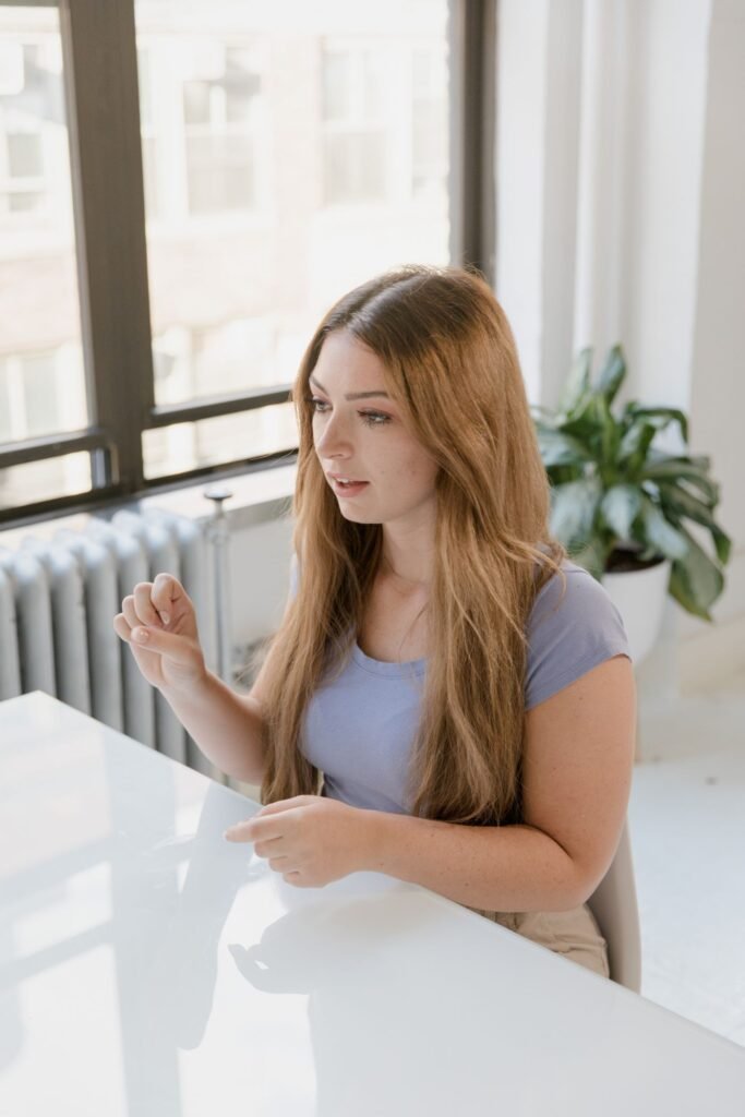 Mulher sentada à mesa se comunicando em língua de sinais