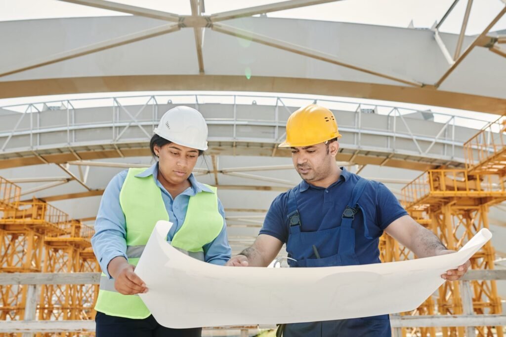 Trabalhadores com capacete analisando uma planta em obra