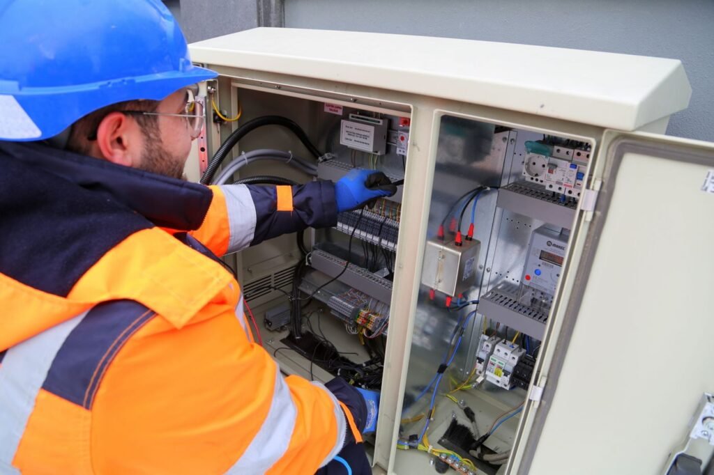 Eletricista com equipamento de proteção trabalhando em painel elétrico