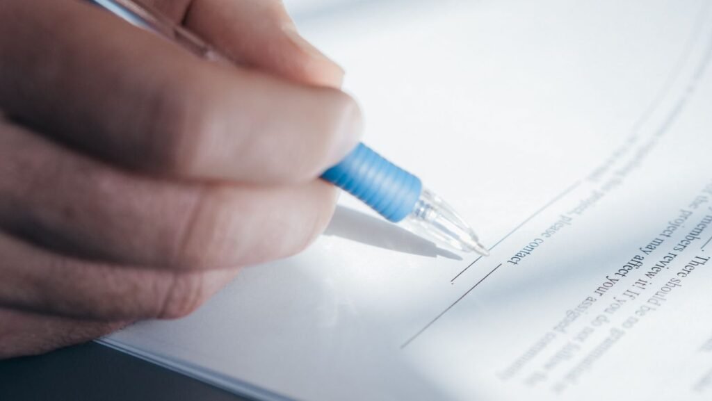 Mão assinando um documento com caneta