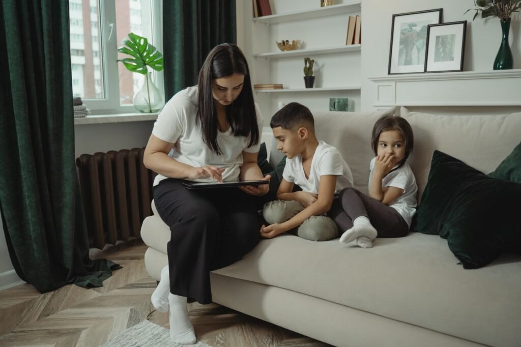 Mãe e filhos sentados no sofá usando um tablet
