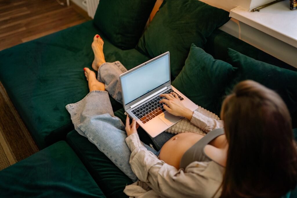 Gestante sentada no sofá usando o notebook