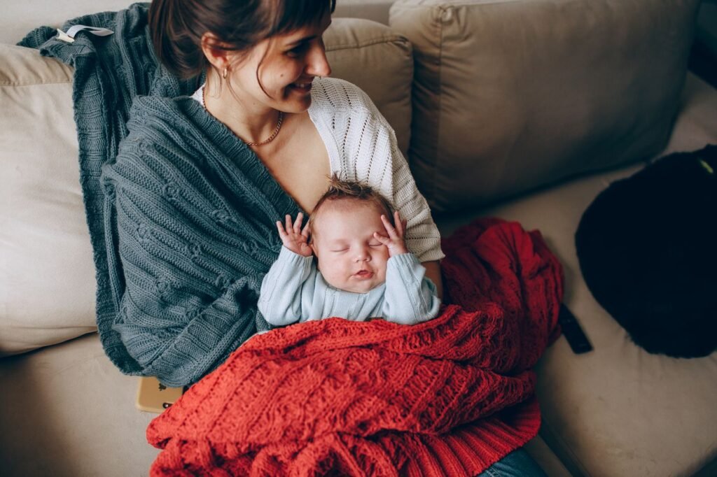 Mãe segurando o bebê dormindo enrolado em uma manta